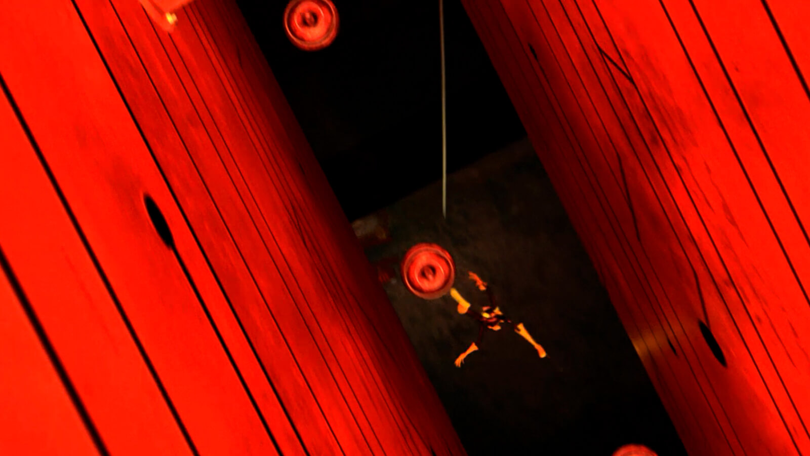 A man falls through a long, narrow pit flanked by glowing red walls