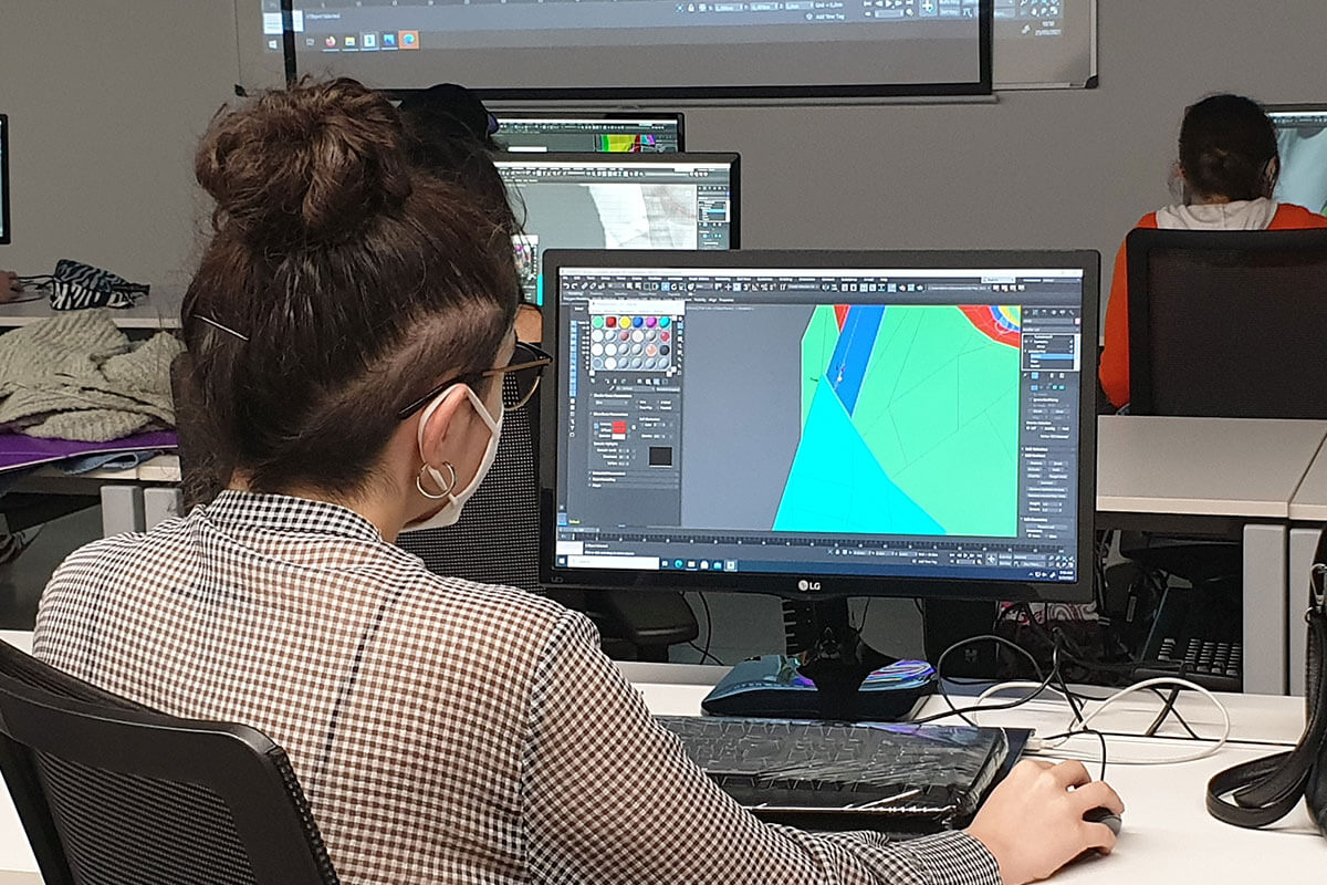 A student sits at a computer using Autodesk Maya.
