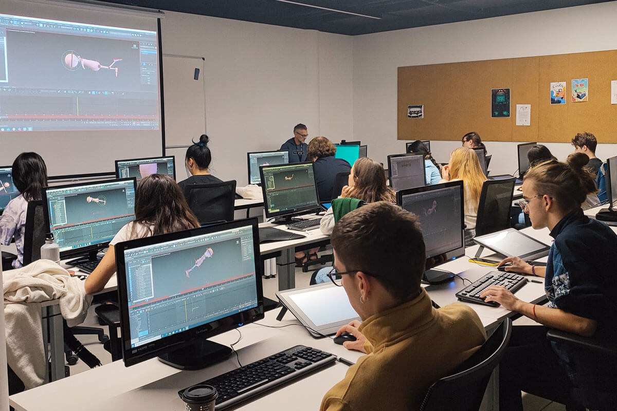Students sit in a classroom behind computers while working on a 3D model.