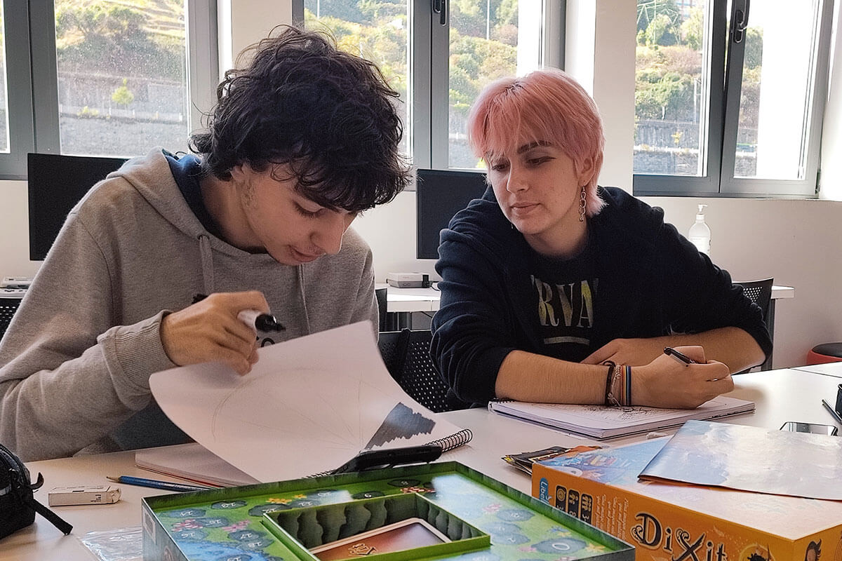 Dos estudiantes de BFA sentados en una mesa colaborando en un boceto artístico.