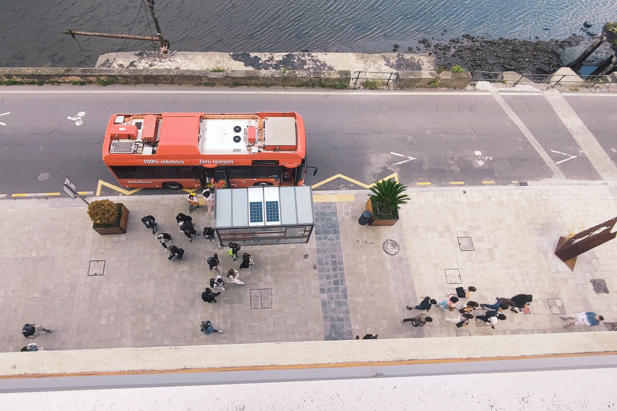 Overhead view of students exiting a city bus and entering the campus building.