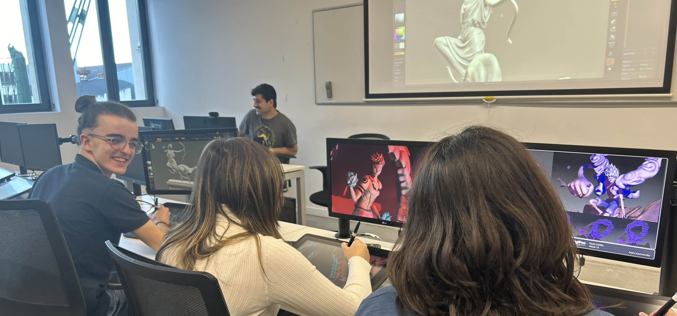 Tres estudiantes esculpen usando ZBrush mientras el instructor enseña con el proyector.