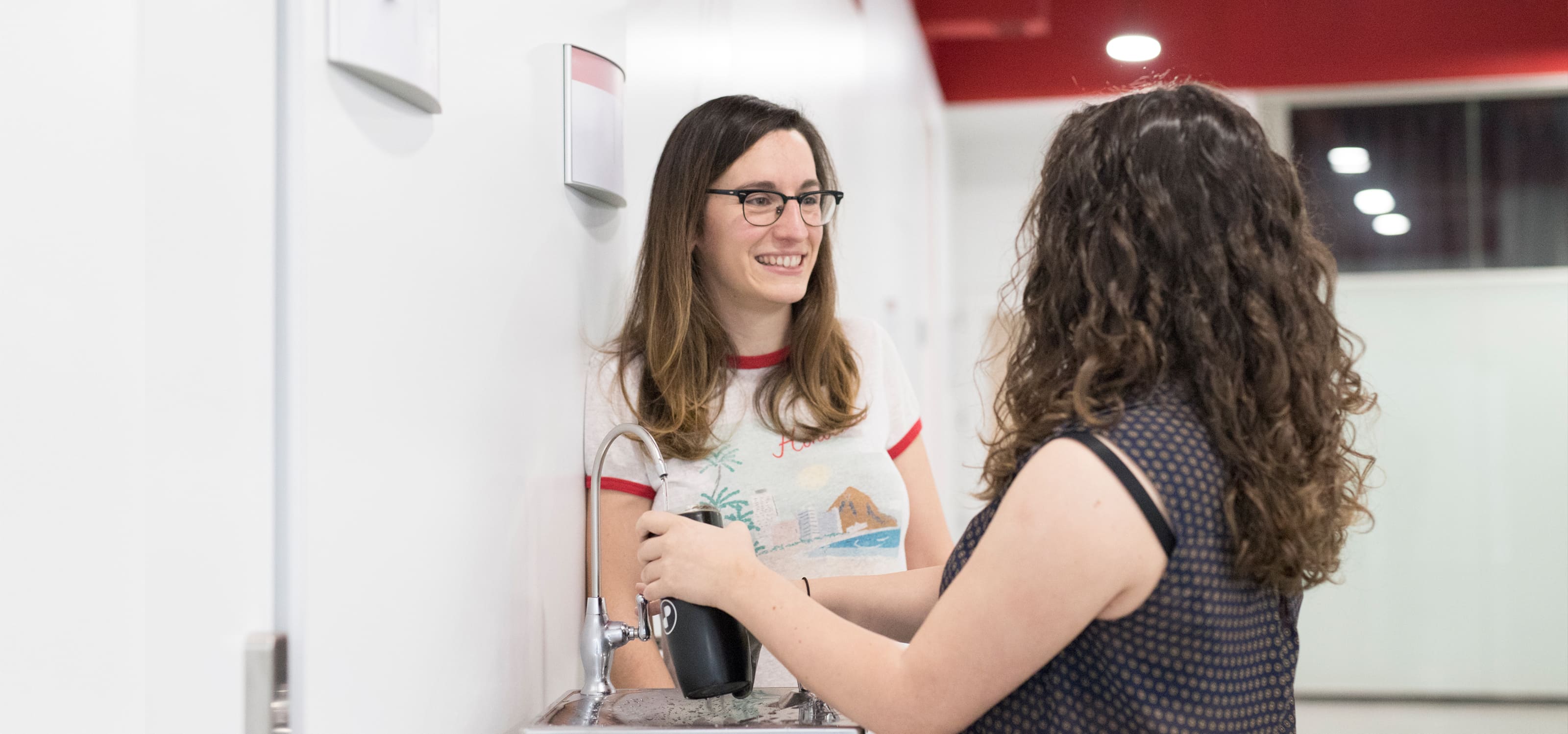 Dos estudiantes de DigiPen Europe-Bilbao conversan cerca del dispensador de agua.