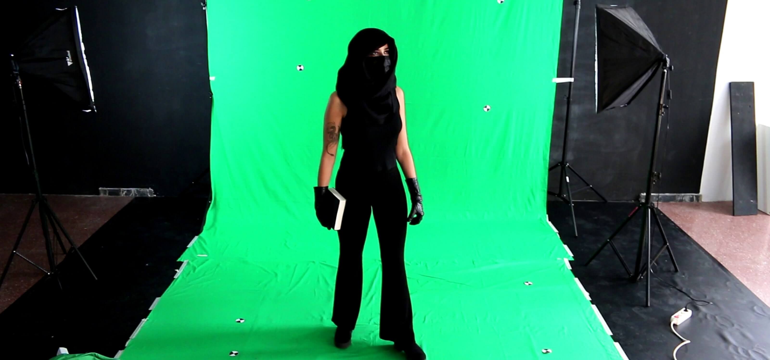 Una estudiante está disfrazada frente a una pantalla verde para efectos especiales.