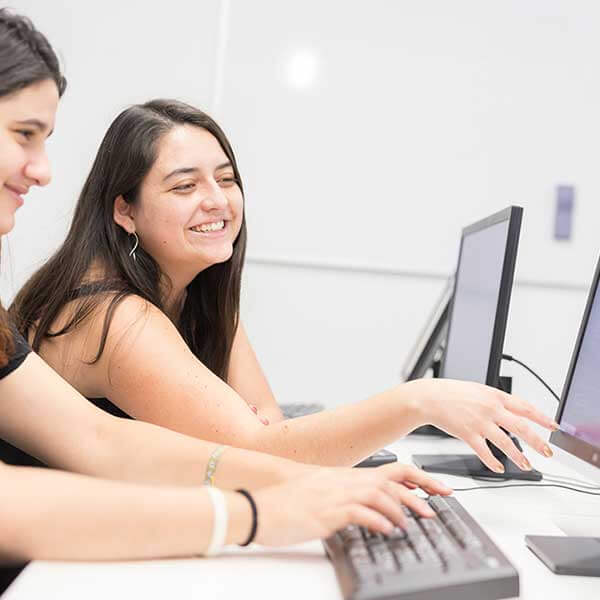 Students laugh as they work at their computer stations