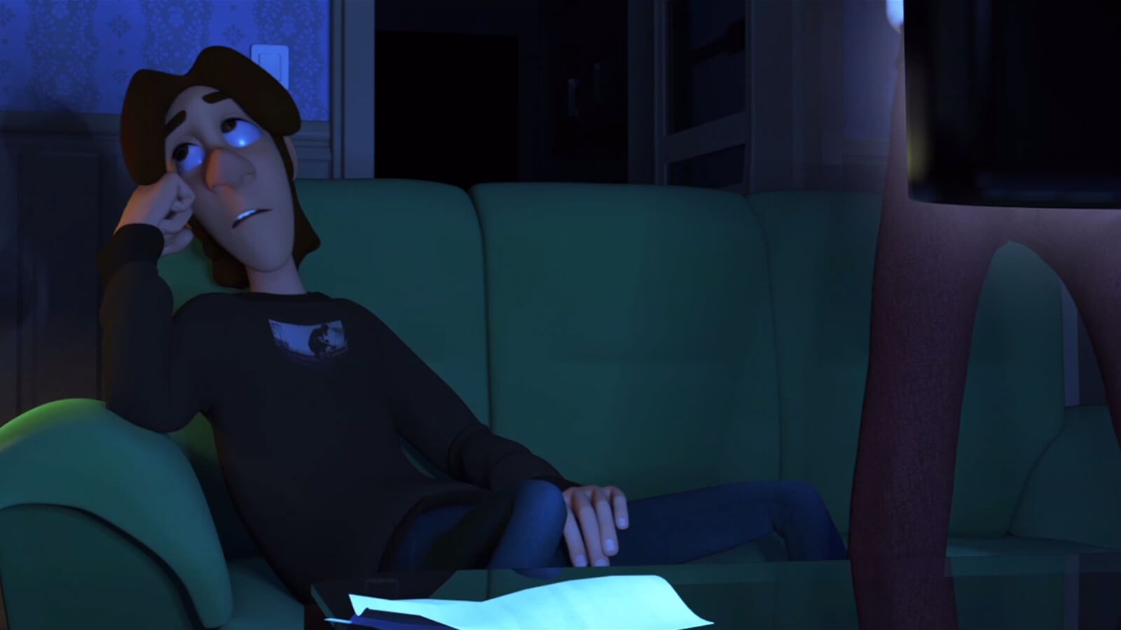 A teenage boy in a black sweater rolls his eyes, sitting on a green couch in a dimly lit room