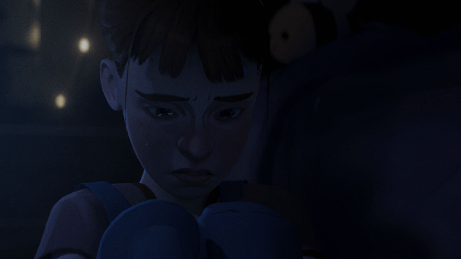 Close-up of a girl crouched and crying at night.