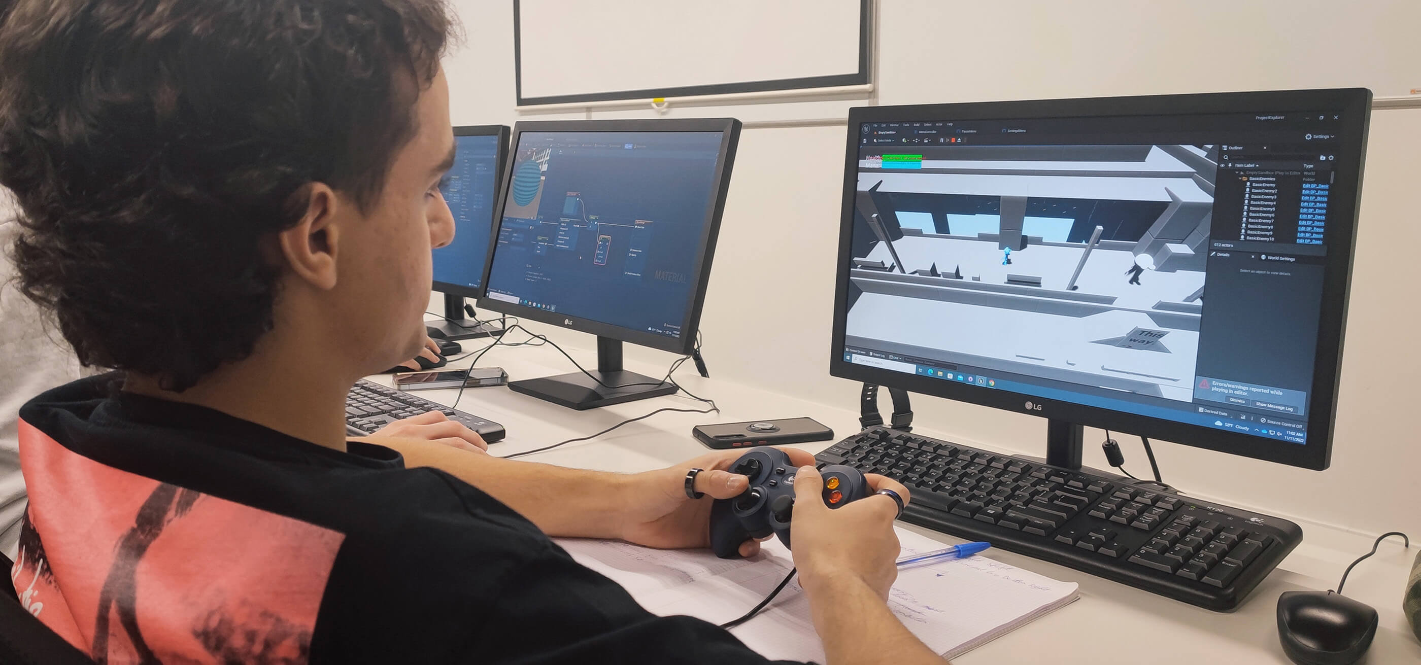 Un estudiante prueba una versión temprana de un juego mientras usa un controlador y mira un monitor.