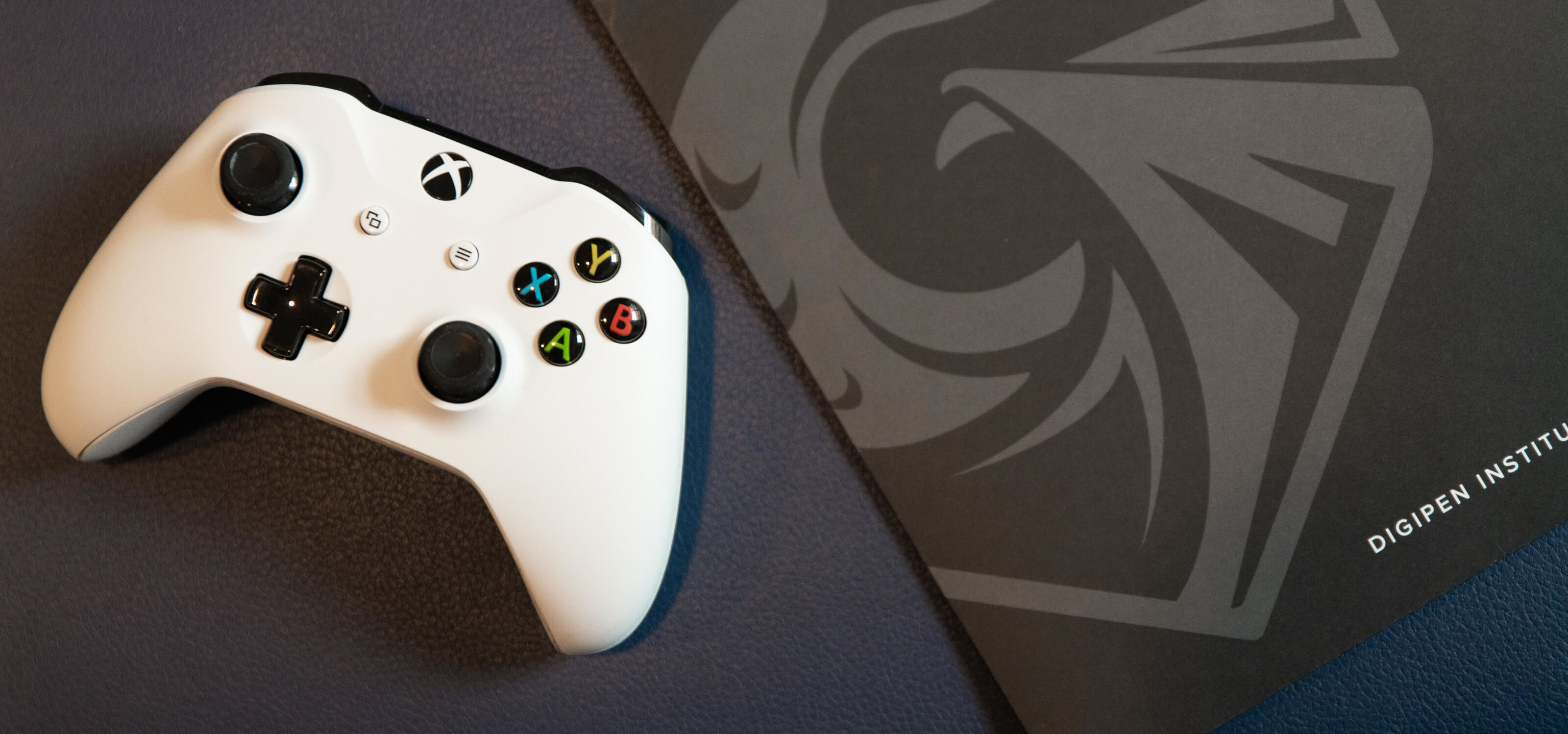 White XBox One controller next to a grey DigiPen folder