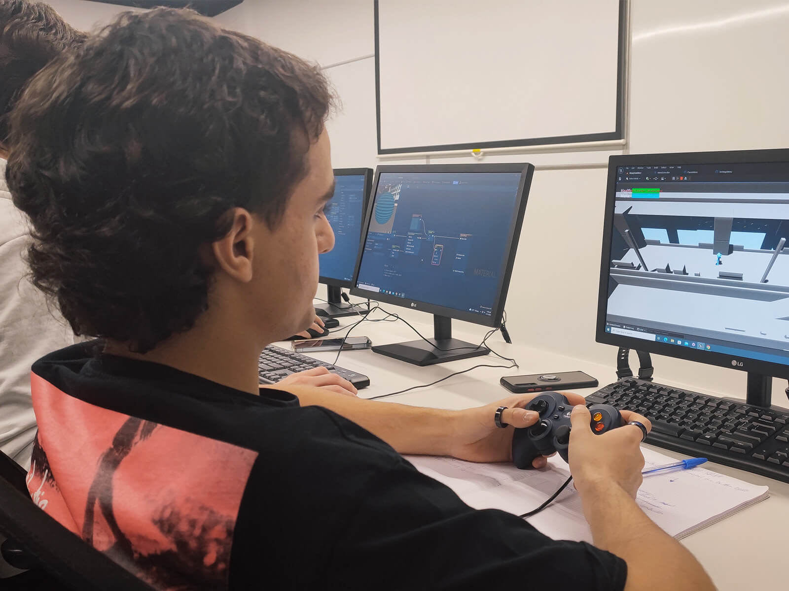 A student playtests an early version of a game while using a controller and looking at a monitor