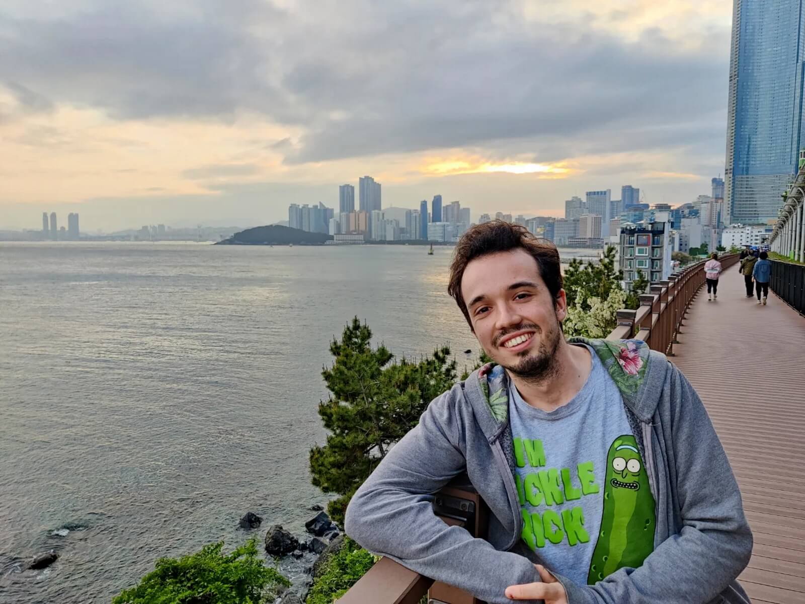 DigiPen alumnus Jon Zapata leans against a railing set against a city skyline next to water