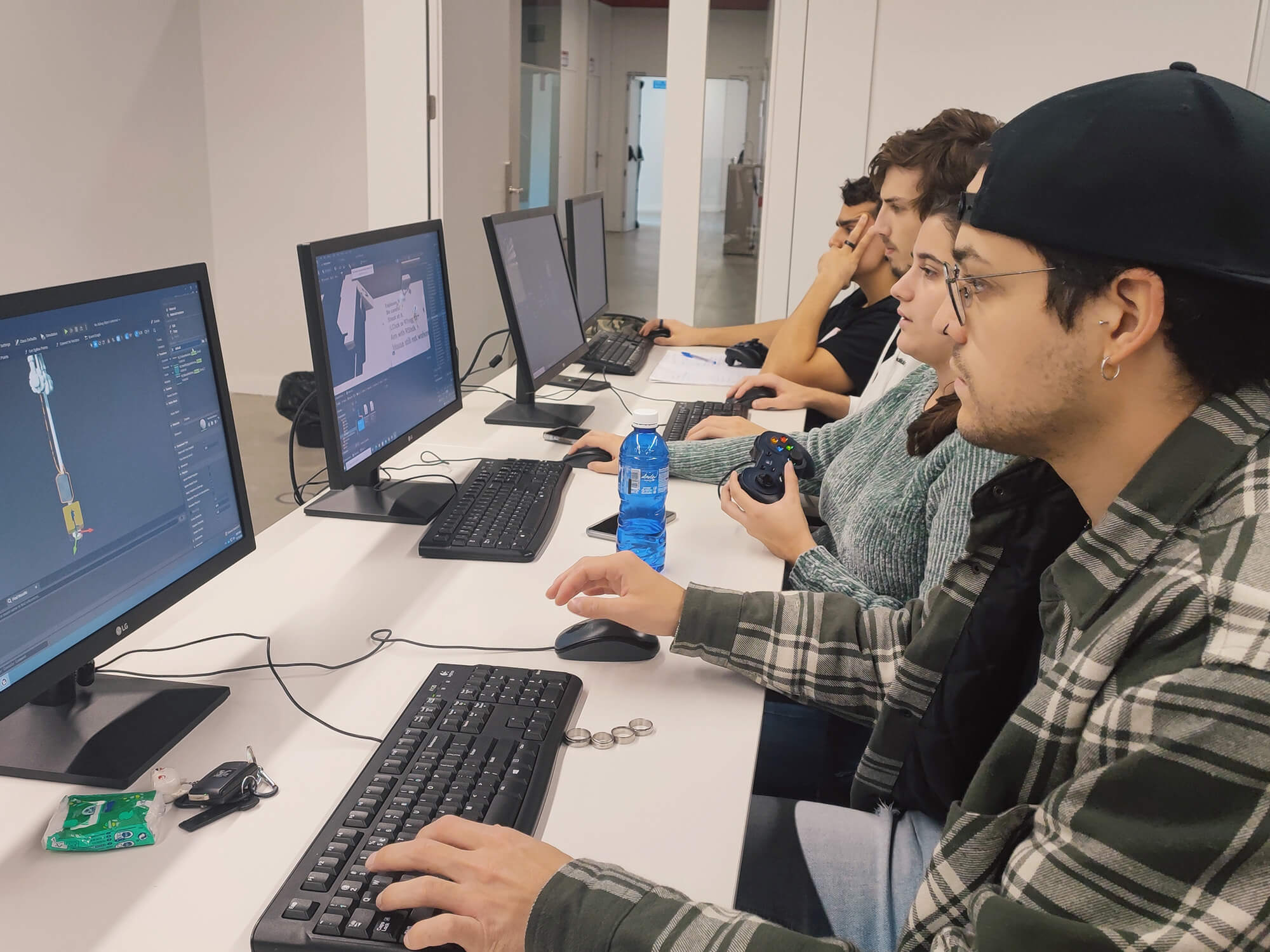 Los estudiantes estan sentados en un escritorio y trabajan en sus proyectos de juegos en sus ordenadores individuales.